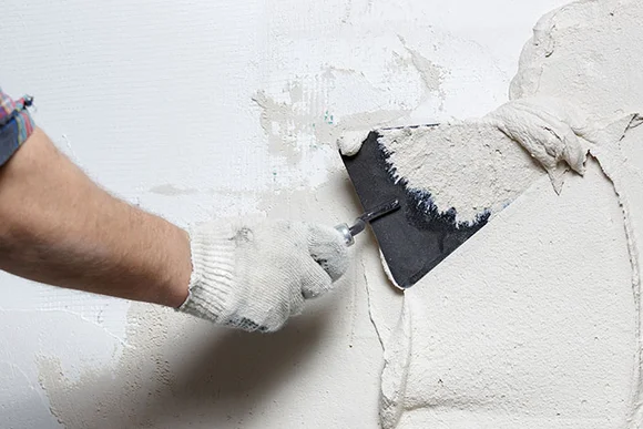 Person trägt Putz auf Wand auf